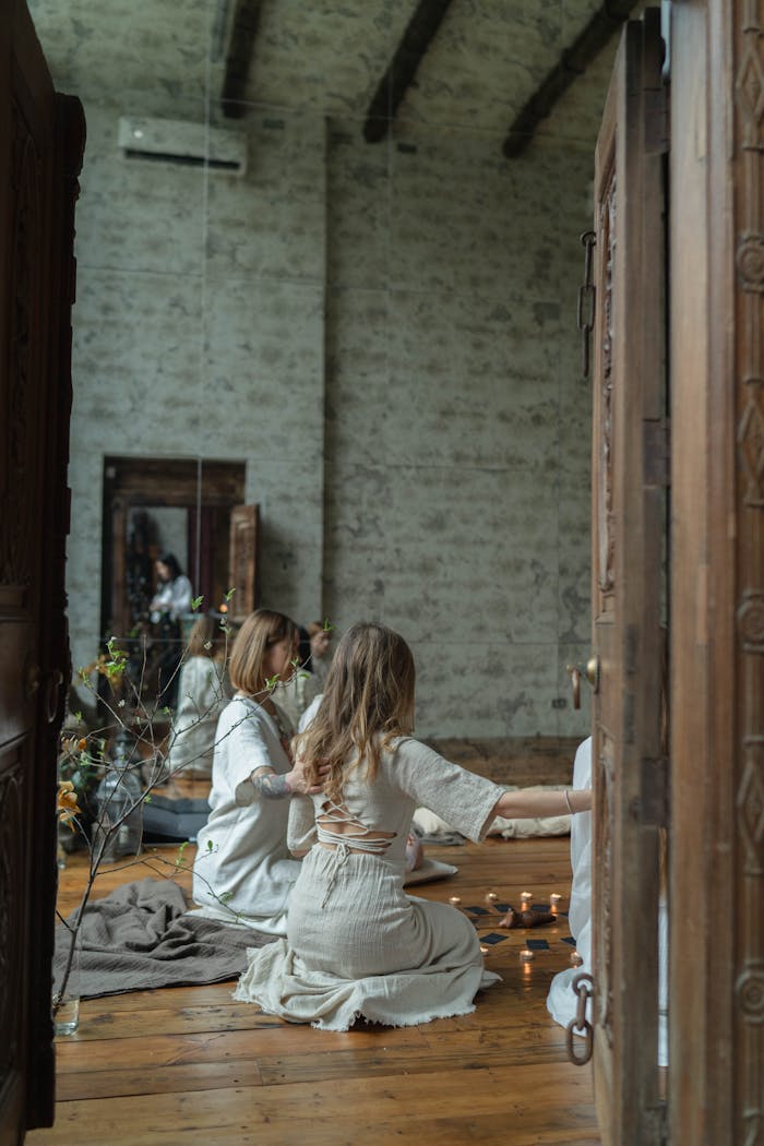 Group of women engaged in spiritual ritual in serene indoor setting with candles.